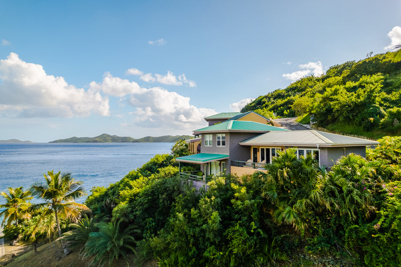 a house on a hill with trees and water in the background